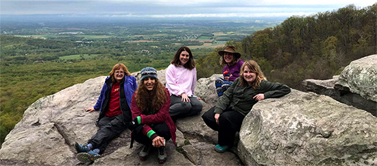hikers on a mountain top with an overlook for miles behind them